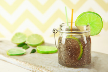Chia seeds beverage with lime in glass jar on striped background