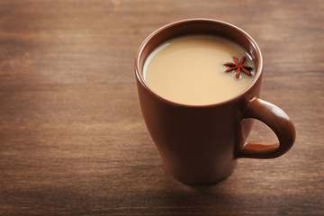 Milk tea with anise on wooden background.