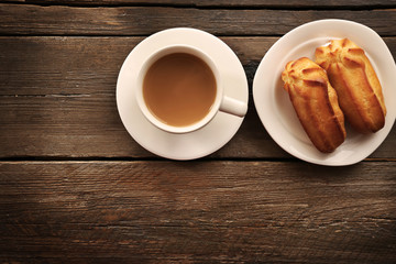 Milk tea with eclairs on wooden background.