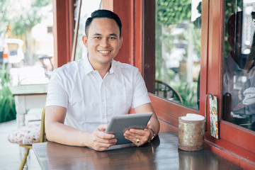 Young successful businessman with tablet in cafe