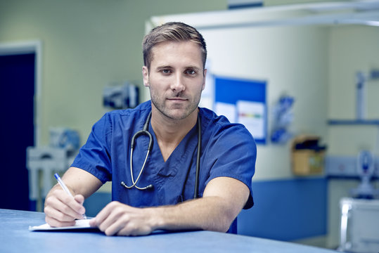 Portrait of male doctor writing up medical notes