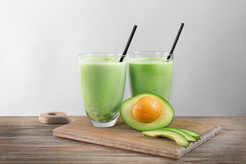 Avocado smoothie and cutting board on grey background