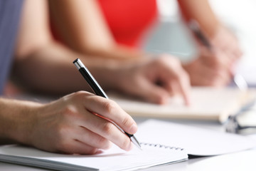 Student's hand writing in exercise book at the table
