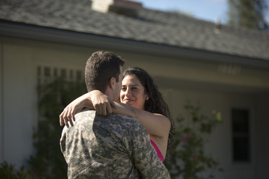 Male soldier hugging wife in garden on homecoming
