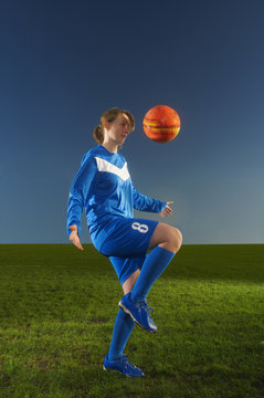 Female footballer playing keepy uppy with ball
