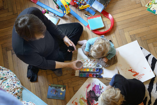 Father and sons painting on floor