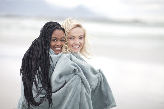 Gay couple wrapped in blanket on beach