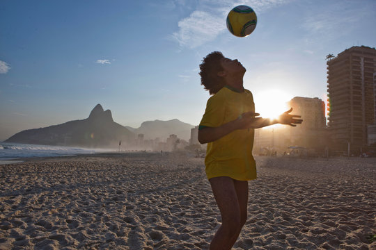Young man heading football, Ipanema Beach, Rio, Brazil