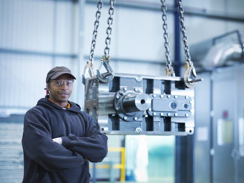 Engineer with industrial gearbox in engineering factory, portrait