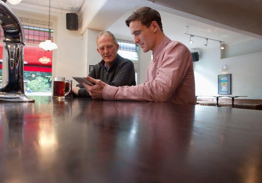 Father and son using digital tablet in bar