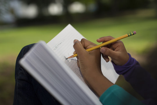 Close up of sisters in park writing in notebook