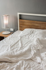 Messy and unmade bed in hotel room on morning time.