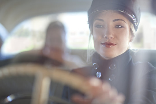 Woman playing chauffeur in vintage car
