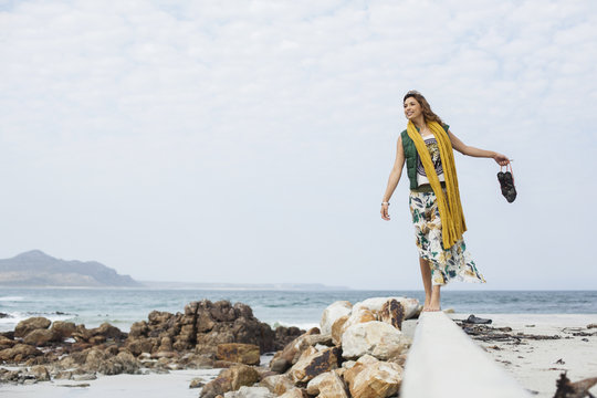 Young woman walking on cement block on beach, Cape Town, Western Cape, South Africa