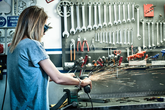 Female mechanic grinding metal in workshop - Powered by Adobe