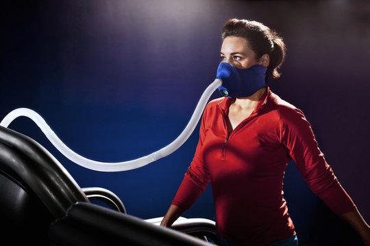 Mid adult woman with face mask on gym treadmill in altitude centre