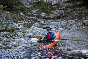 Mid adult man moving kayak from waters edge into river