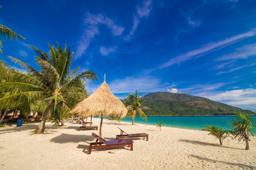 Vacation time background of two beach lounge chairs under grass