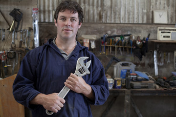 Portrait of mature man holding wrench in boat workshop