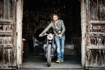 Mid adult man pushing motorcycle out of barn doorway © Connect Images