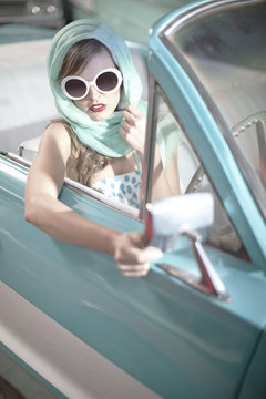 Woman in headscarf and white sunglasses in vintage convertible