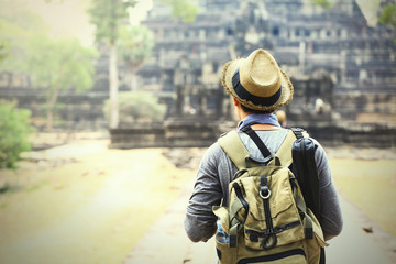 Young traveler wearing a hat with backpack and tripod - at Angkor Wat, Siem Reap, Cambodia (very...