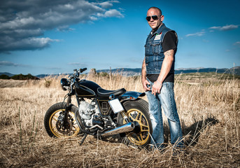 Portrait of male motorcyclist in plain landscape, Cagliari, Sardinia, Italy © Connect Images