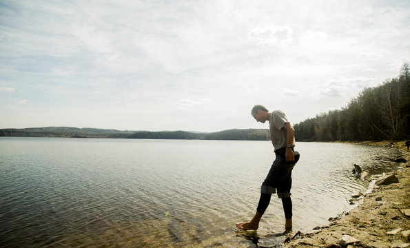 Young male hiker taking apprehensive paddle in lake