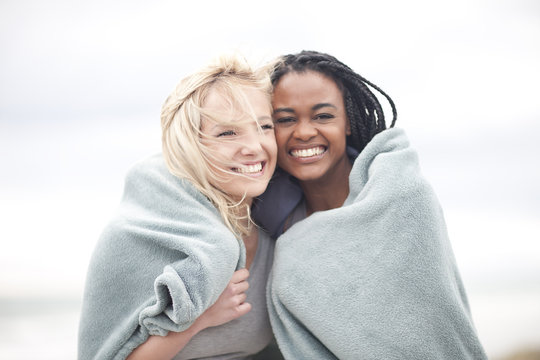 Gay couple wrapped in blanket on beach