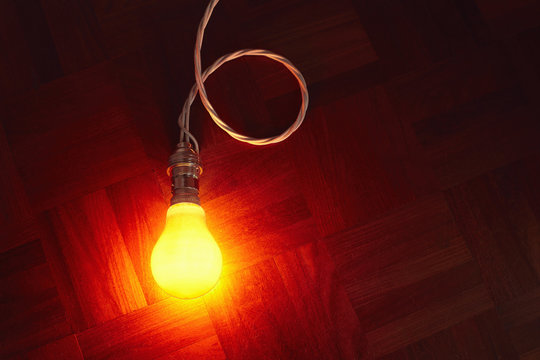 Still life of glowing lightbulb on parquet floor