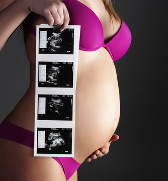 Pregnant woman holding ultrasound pictures