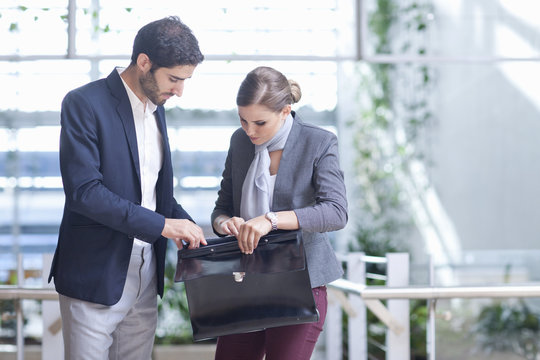Businessman and businesswoman opening briefcase in conference centre atrium