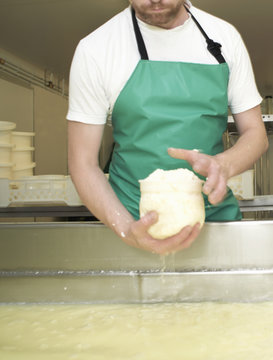 Cheesemaker moulding curds at farm factory
