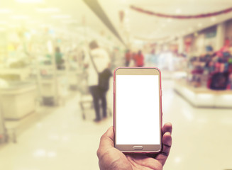 Hand with smartphone on blurred in shopping mall background