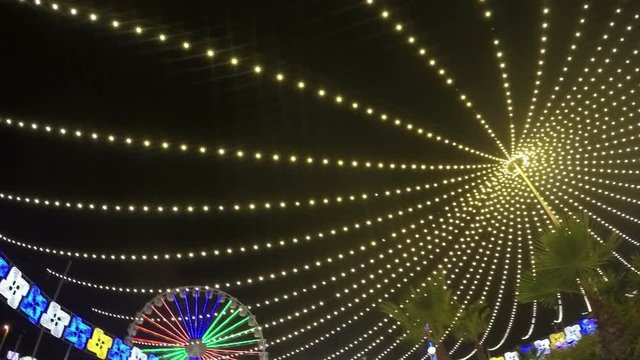 Slow motion of many lights in amusement park at night.