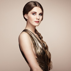 Fashion portrain of young beautiful woman in gold dress. Brunette glamour lady with perfect make up and hairstyle