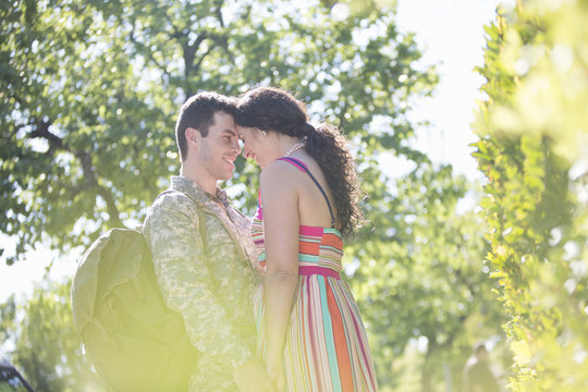 Male soldier holding hands with wife on street at homecoming