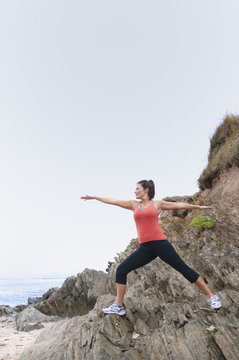 Mature woman exercising on rocks
