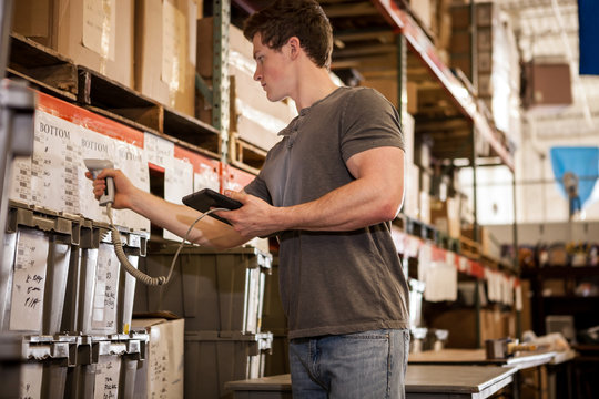 Worker in warehouse scanning barcode on cardboard box