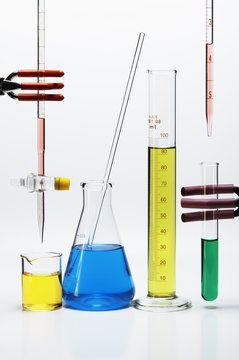 Chemical lab glassware: burette over beaker, Erlenmeyer flask with stirring rod, graduated cylinder, pipette over test tube