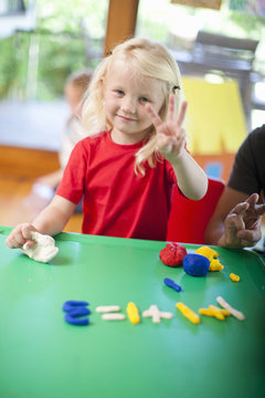Portrait of girl counting with fingers at nursery school