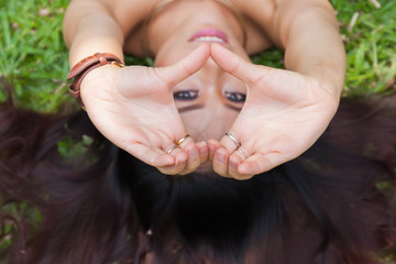 Young woman laying down and putting hands together in heart shape