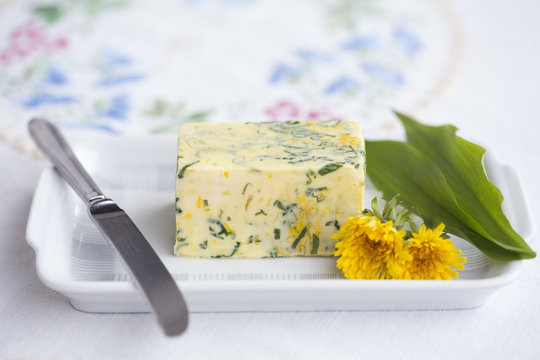 Wild garlic (Allium ursinum) butter with dandelion flower and leaves on butterdish