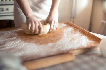Baker hands kneading dough in flour 

on table