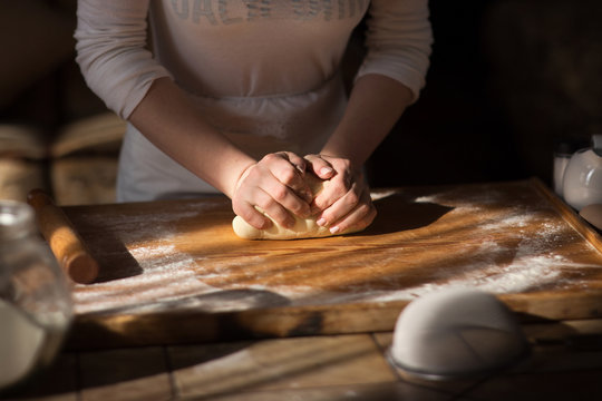 Baker hands kneading dough in flour 

on table
