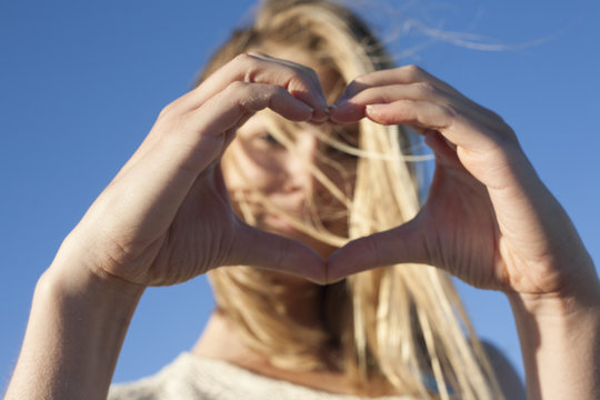 Young woman making heart sign with hands, Breezy Point, Queens, New York, USA