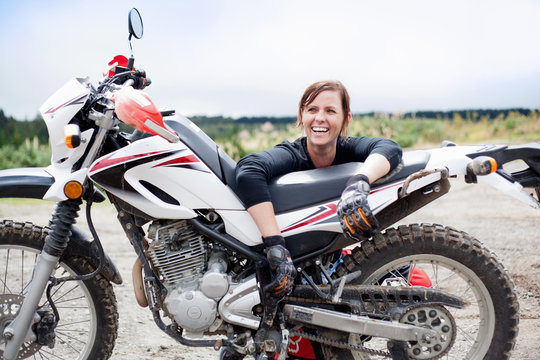 Portrait Of Smiling Young Adult Female Motorcyclist With Motorcycle