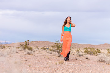 Attractive fashionable young woman in the desert walking in pink skirt