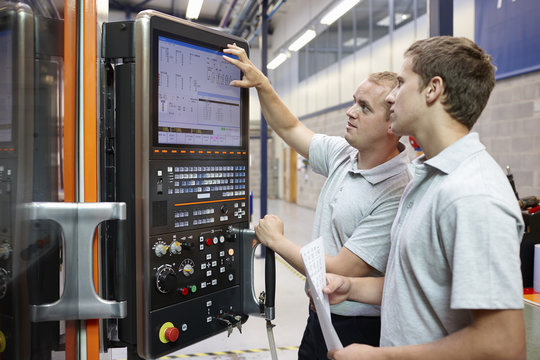 Workers looking at computer monitor in engineering factory