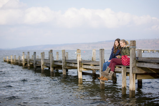 Teenage girls sitting on jetty